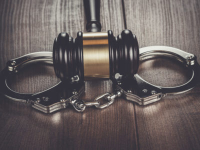 handcuffs and judge gavel on brown wooden table handcuffs and judge gavel on brown wooden table background